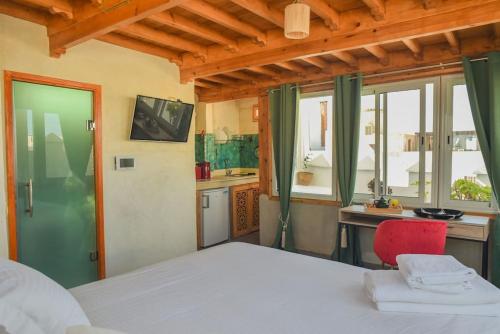 a bedroom with a bed and a kitchen with a window at Stella 4 - studio deluxe, rooftop en médina in Essaouira