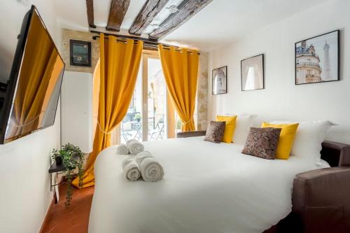 a bedroom with a large white bed with yellow curtains at Sweety home in center of Paris in Paris