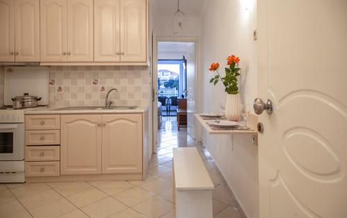 a kitchen with white cabinets and a vase of flowers on the counter at Ethereal Villas Lefkas in Nydri
