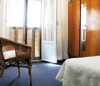 a bedroom with a bed and a chair and a door at Hotel Pierre Loti in Juan-les-Pins