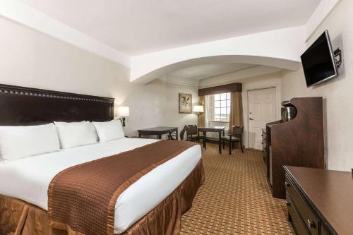 a hotel room with a bed and a desk at Baymont by Wyndham Galveston in Galveston