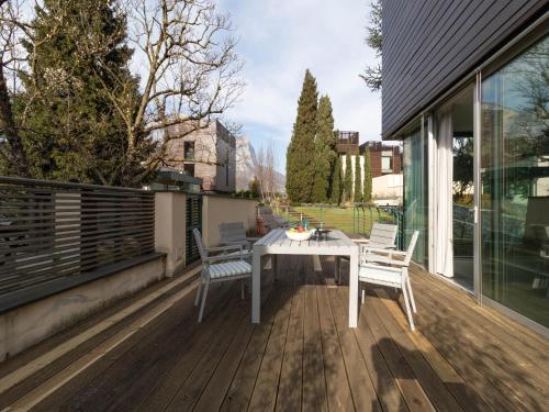 un tavolo bianco e sedie su una terrazza in legno di Mamma Ciccia - ecofriendly villa on Lake Como a Malgrate