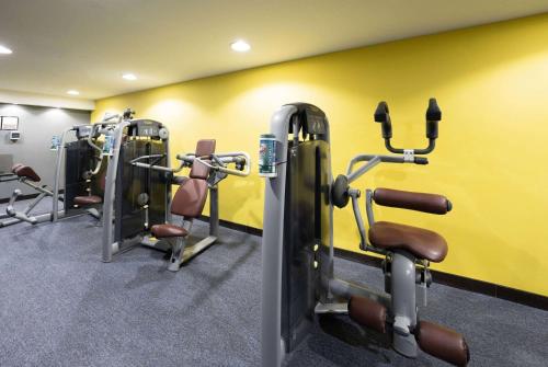a gym with several tread machines and a yellow wall at Ramada Encore Doha by Wyndham in Doha