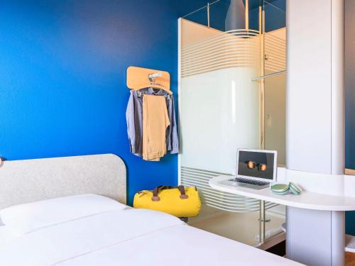 a bedroom with a bed and a table with a laptop at Ibis budget Lausanne-Bussigny in Lausanne