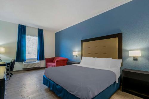 a bedroom with a large bed and a red chair at Rodeway Inn Wesley Chapel in Wesley Chapel