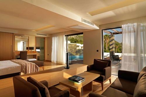 a hotel room with a bed and a living room at Wyndham Loutraki Poseidon Resort in Loutraki