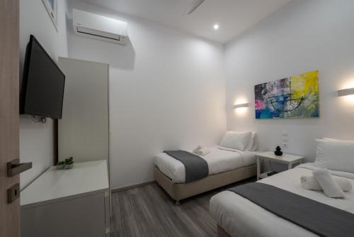 a bedroom with two beds and a flat screen tv at Central Suites Aegina 2 in Aegina Town