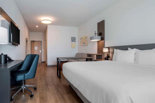 a hotel room with a large white bed and a desk at Comfort Inn & Suites Panama City Beach - Pier Park Area in Panama City Beach