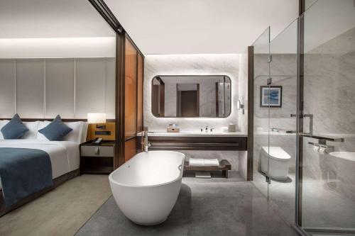 a hotel room with a tub and a bed and a bathroom at Wyndham Xiong'an in Baoding