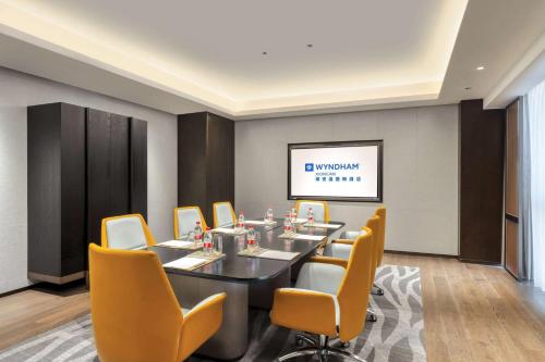 a conference room with a table and yellow chairs at Wyndham Xiong'an in Baoding