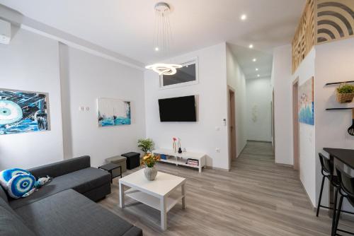 a living room with a couch and a tv on the wall at Central Suites Aegina 2 in Aegina Town