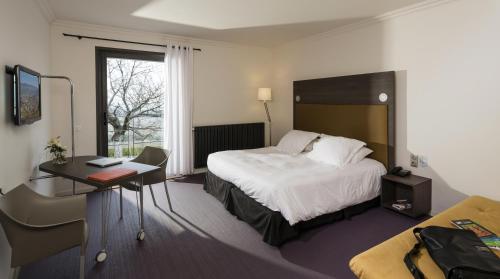 ein Hotelzimmer mit einem Bett und einem Schreibtisch in der Unterkunft Hôtel Restaurant La Montagne De Brancion in Martailly-lès-Brancion