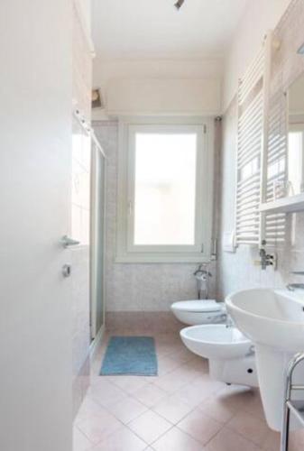 a white bathroom with two sinks and two toilets at Casa Davide in Sottomarina