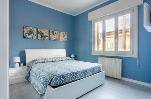Dormitorio azul con cama y ventana en Casa Davide, en Sottomarina