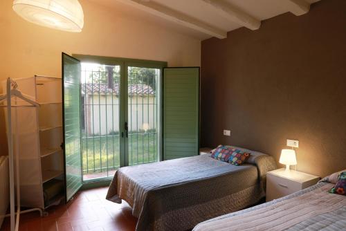 1 dormitorio con 2 camas y ventana en Masia Rural Cal Belles Mas, en Riudarenes