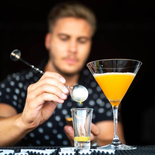 a man sitting at a table with a drink and a spoon at Füzeskerti Apartmanház in Békésszentandrás