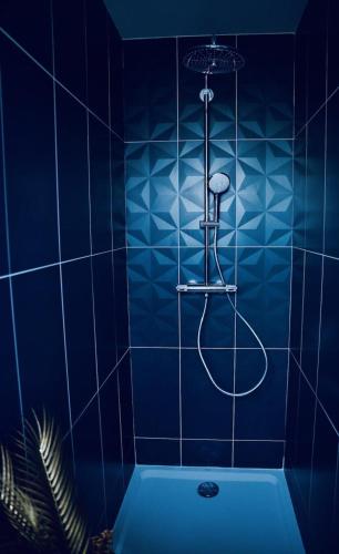 baño de azulejos azules con bañera y ducha en L'Evasion chambre MONTMARTRE avec Jacuzzi privatif en Prinquiau