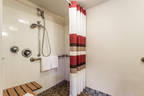 W łazience znajduje się prysznic z czerwono-białą zasłoną prysznicową. w obiekcie Red Roof Inn Milwaukee Airport w mieście Oak Creek