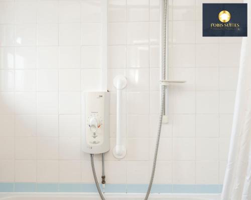 y baño con ducha y pared de azulejos blancos. en Fobis Suites Short Lets for 3 Bed Family Group Contractors Dagenham, en Dagenham