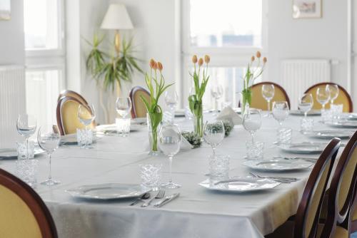 a long white table with plates and wine glasses at Lila Medical SPA in Ciechocinek