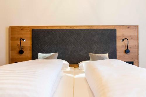 a bedroom with two beds with white sheets and lights at Hotel zur Post in Lam