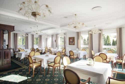 a dining room with tables and chairs and chandeliers at Lila Medical SPA in Ciechocinek