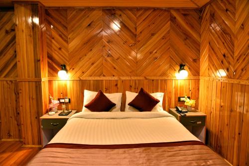 a bedroom with a large bed with wooden walls at Rufina Lachung Kunga in Lachung