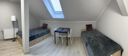 Cette chambre comprend 2 lits, une table et une fenêtre. dans l'établissement Pokoje na Górce, à Rajgród