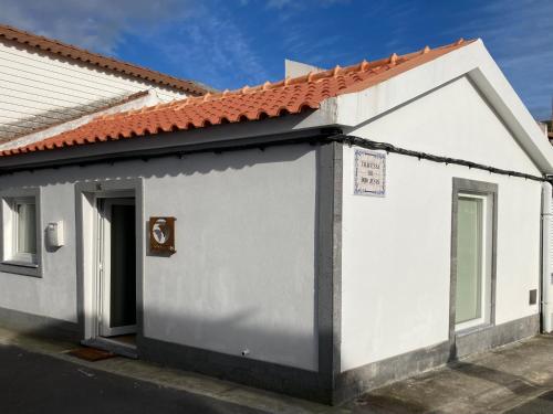 a small white building with a red roof at Alojamento confortável a 2 min da Praia in Horta