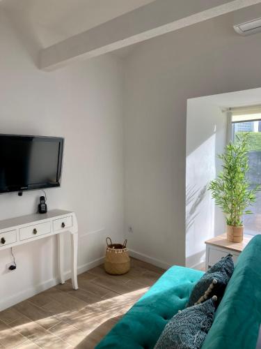a living room with a green couch and a flat screen tv at Alojamento confortável a 2 min da Praia in Horta