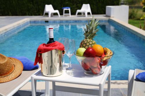 a table with a bucket of fruit and a bottle of wine at Xenos Villa 6 with a Private pool near the sea in Tigaki