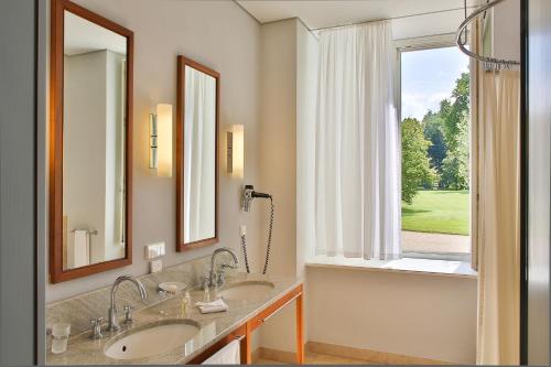 a bathroom with two sinks and a large window at Hotel Schloss Neuhardenberg in Neuhardenberg