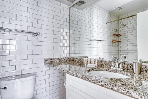 a white tiled bathroom with a sink and a toilet at Dupont 2BR w Patio WD nr nightlife WDC-340 in Washington, D.C.