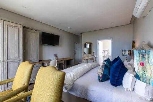 a bedroom with a large bed with two yellow chairs at Hermanus Boutique Guest House in Hermanus