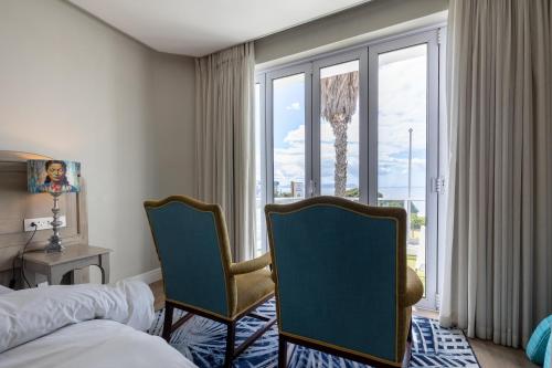 a hotel room with a bed and two chairs and a window at Hermanus Boutique Guest House in Hermanus