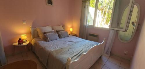 a bedroom with a bed with two lamps and a window at Petite maison au calme garrigue et mer Montpellier in Teyran