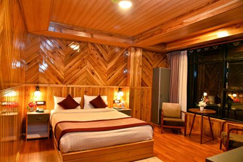 a bedroom with a bed in a room with wooden walls at Rufina Lachung Kunga in Lachung