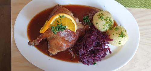 a white plate of food with meat and purple cabbage at Hotel zur Post in Lam