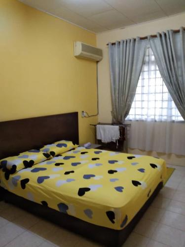 - une chambre avec un lit et une couette jaune en bleu dans l'établissement NF Homestay near to UUM Sintok, à Changlun