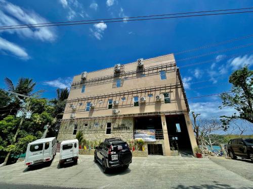 un edificio con dos vehículos estacionados frente a él en Hotel Dorotea, en Puerto Galera