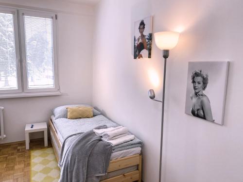 um quarto com uma cama com um candeeiro e fotografias na parede em Apartman JakoDoma em Ceská Lípa