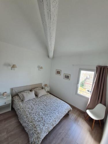 a bedroom with a bed and a window and a chair at Le Repaire du Soleil in Aigues-Mortes