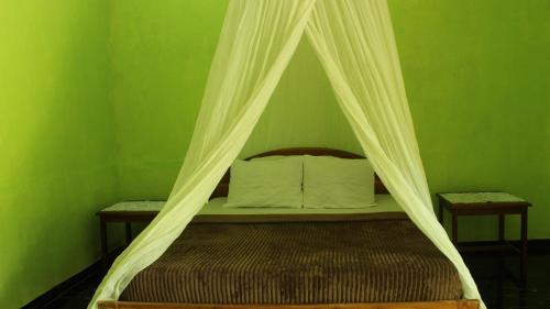 a bed with a canopy in a green bedroom at Balo Surf House in Nembrala