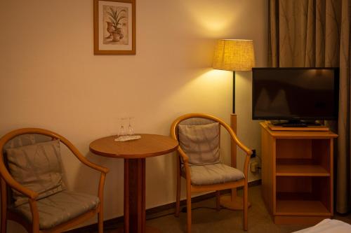 Zimmer mit einem Tisch, 2 Stühlen und einem TV in der Unterkunft Nostalgie Altstadt Hotel Kornpforte by 42 in Koblenz