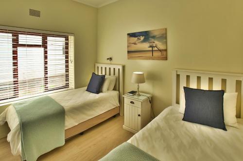 a bedroom with two beds and a window at Sea Cottage in Langebaan