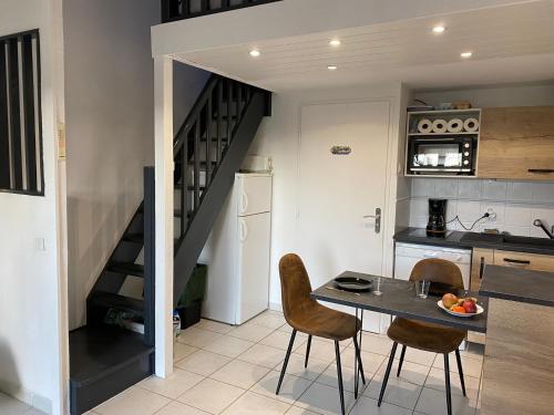 uma cozinha com uma mesa e cadeiras e uma escadaria em Villa Domaine des Pins, Magasins proches, Piscine em Fréjus
