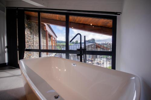 a bath tub in a bathroom with a large window at Hotel Rural O Cruce do Burgo in Friol