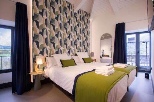 Hotel Rural O Cruce do Burgo في Friol: غرفة نوم بسرير كبير وملاءات خضراء وبيضاء