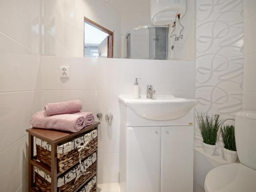 a white bathroom with a sink and a mirror at Apartament Kameralny na Starówce in Gdańsk