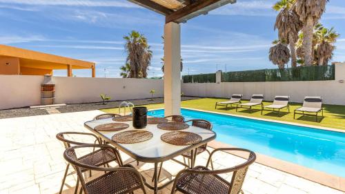un patio con mesa y sillas junto a una piscina en Villa Jarcia by Calima Villas, en Caleta de Fuste